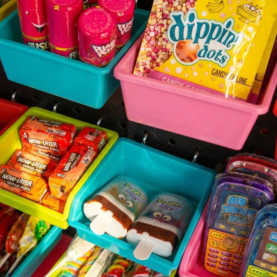 Colorful bins display assorted candies, lollipops, Dippin’ Dots candy, Now and Later chews, and novelty candy containers.